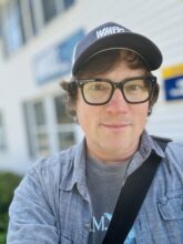 Photo of Bobby Shaddox with glasses and wearing a WMPG baseball cap