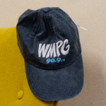 Picture of a gray hat resting on the edge of a plush-yellow chair.