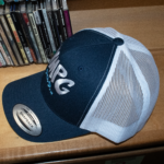 Picture of the side profile of the WMPG navy blue snapback sitting on a wooden table.