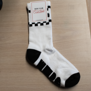 Picture of the WMPG checkered socks still in the packaging on a beige background.