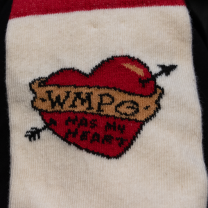 Picture of a close-up detail from the heart socks. This is of the decal which is a red heart with an arrow through it, a banner going across the heart that says WMPG and text below the banner on the heart says "has my heart."