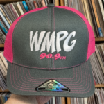Picture of a hand holding a gray snapback with pink mesh on the back of the hat.